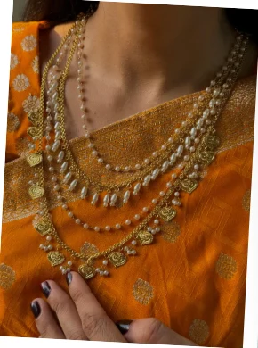 Legacy by Bisma layered pearl and gold mala over an orange saree